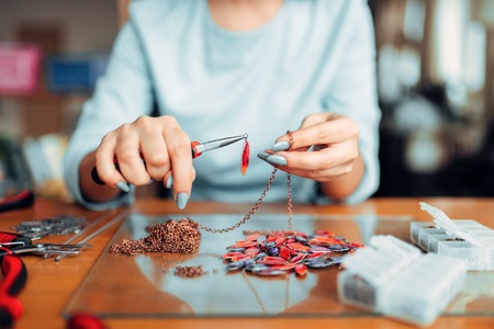 Female person holds pliers, bijouterie making