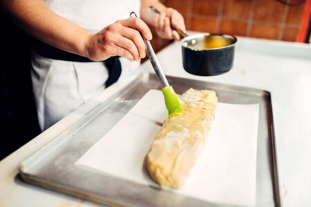 Chef hand lubricates strudel with egg and butterの写真素材
