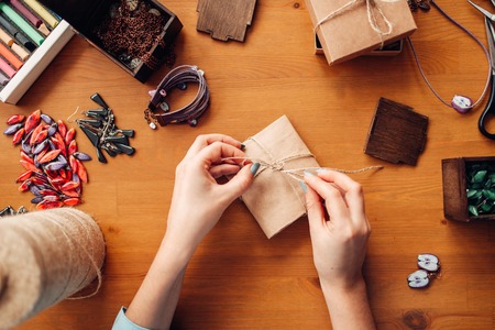 Female person tie a bow on a gift box, needlework