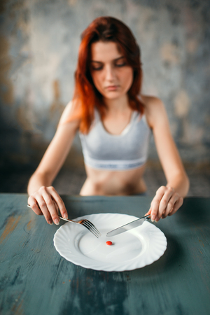 Woman against plate with a tablet for weight lossの写真素材