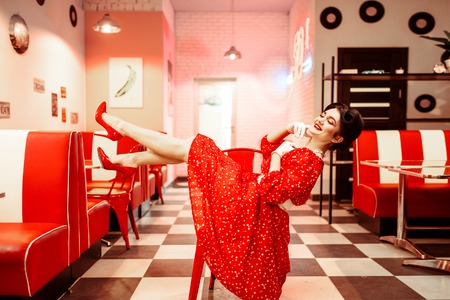 Sexy pin up girl with makeup posing in retro cafeの写真素材