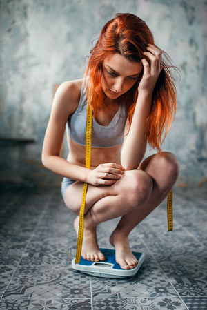 Thin woman in underwear weighed on a scaleの写真素材