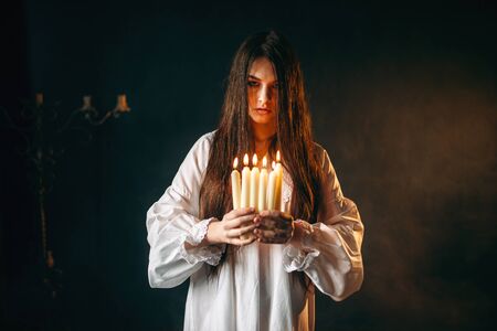 Female person holds candles in hands, divination