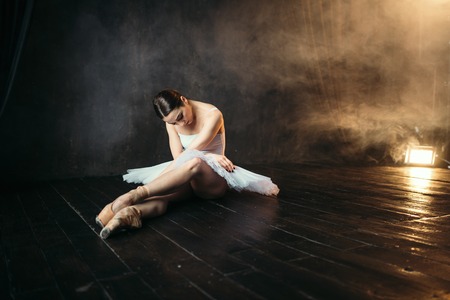 Ballerina in white dress sitting on stageの写真素材