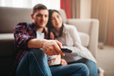 Couple sitting on the floor hugs and watch movie