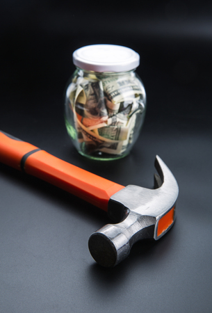Hammer against jar full of dollars, money savingの写真素材