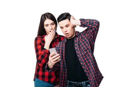Phone addiction, surprised couple looks on screenの写真素材