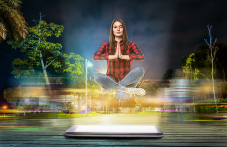 Woman in yoga pose hovers above a big phoneの写真素材