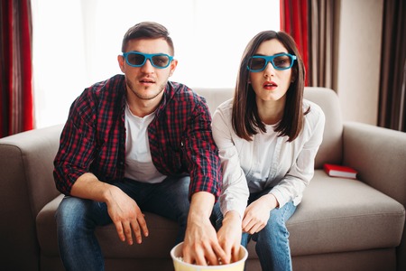 Bewitched couple watch tv and eats popcorn at home