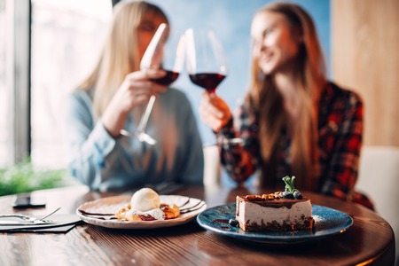 Girlfriends drinks red wine and eats dessertの写真素材