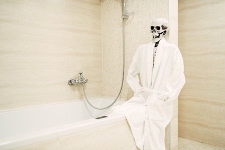Human skeleton sitting on the edge of the bathの写真素材