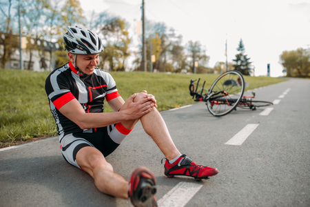 Male bycyclist fell off bike and hit his kneeの写真素材