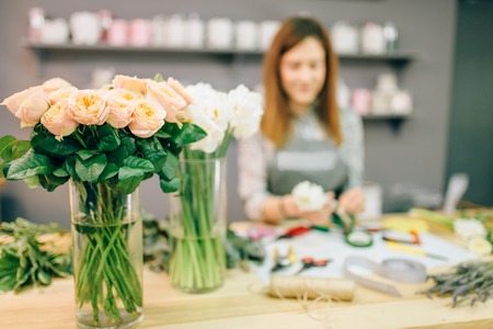 Female florist prepares rose bouquet at workplaceの写真素材