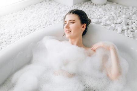 Attractive lady lying in bath with foam, top viewの写真素材