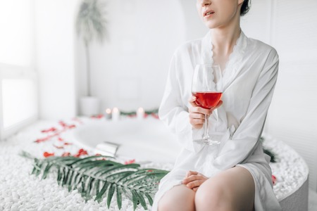 Woman sitting in bath decorated with rose petalsの写真素材