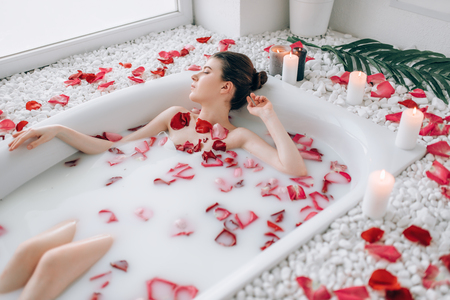 Sexy lady lying in bath with foam and rose petalsの写真素材