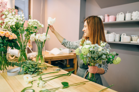 Female florist places flowers in vasesの写真素材