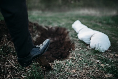 Male murderer with a shovel  is digging a graveの写真素材
