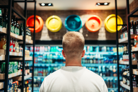 Male customer choosing drinks in supermarketの写真素材
