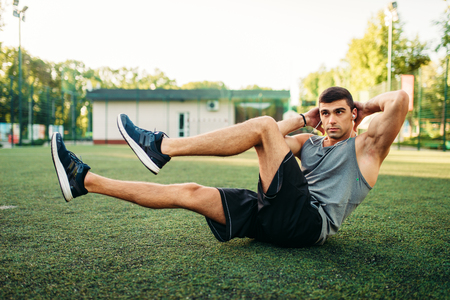 Male athlete doing exercises on the press outdoorの写真素材