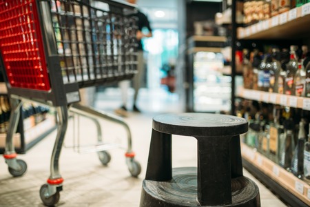 Shopping cart between shelves with alcohol drinksの写真素材