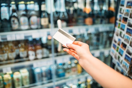 Female hand with credit card, alcohol marketの写真素材