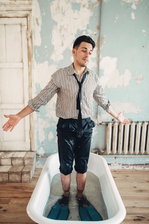 Beginning businessman in flippers stands in bathの写真素材