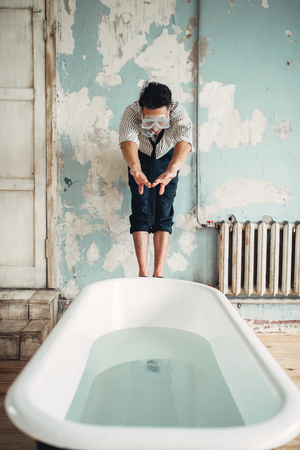 Businessman in flippers dives into the bathtub