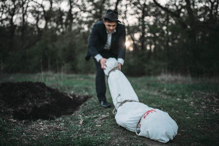 Slayer drags the victims body into a graveの写真素材