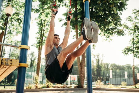 Man doing exercise on press using horizontal barの写真素材