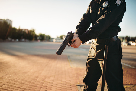 Male cop in uniform with gun in handsの写真素材