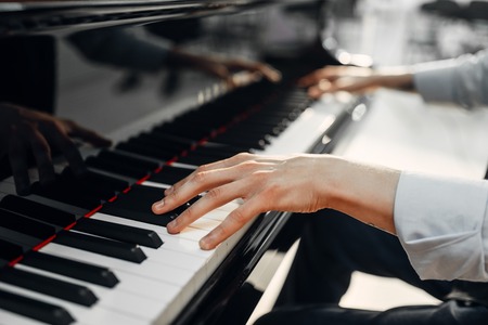 Male pianist hands on grand piano keyboardの写真素材