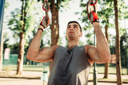 Athletic man pulled up on sport rings outdoor