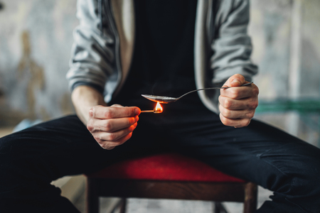 Junkie hands with spoon and matches prepares doseの写真素材