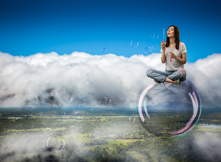 Cute woman flying in the sky on big soap bubbleの写真素材