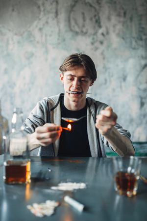 Drug addict with spoon and matches prepares a doseの写真素材