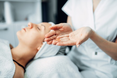 Beautician hands with cream against female patientの写真素材