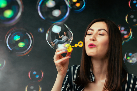 Young woman blows colorful soap bubblesの写真素材