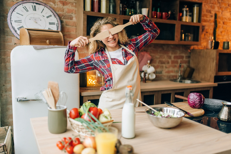Housewife covers her eyes with wooden spatulasの写真素材