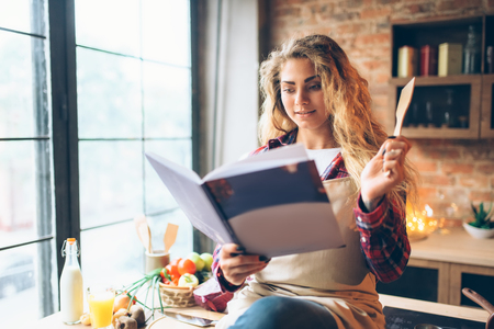 Young housewife in an apron reads recipe bookの写真素材