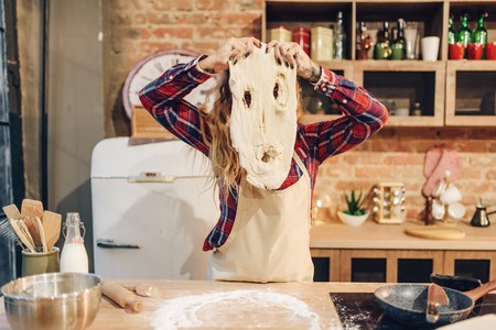 Playful housewife in an apron indulges with doughの写真素材
