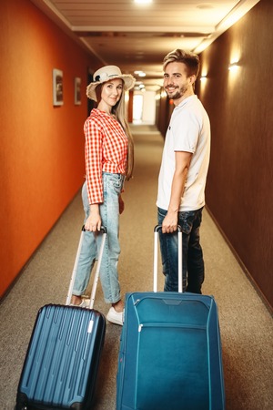 Smiling couple with suitcase in hotel hallwayの写真素材