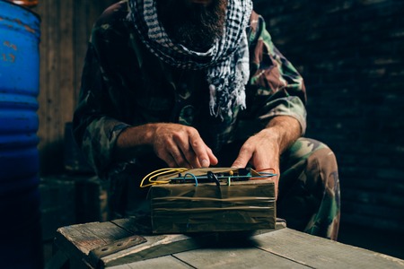 Bearded terrorist in uniform cooking a bomb