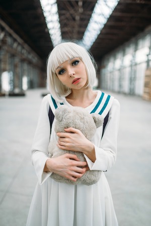 Anime style blonde girl hugs teddy bear