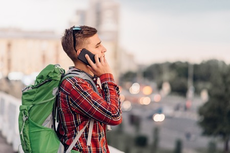 Male tourist with backpack talking by phone