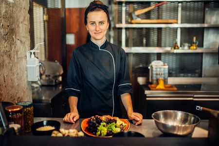 Female chef cooking meat salad on wooden table