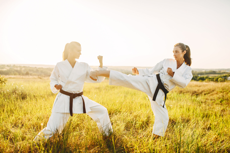 Two female karate in kimono fight in summer fieldの写真素材