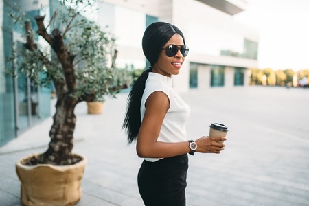 Business woman in sunglasses with coffee outdoors