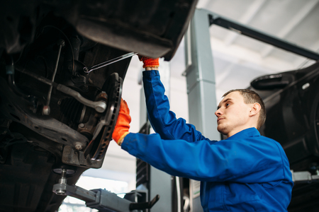 Mechanic with wrench repairs the suspension of carの写真素材
