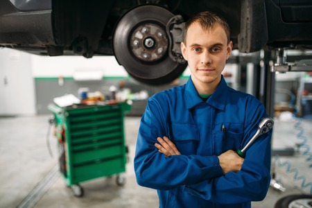 Repairman with wrench against a car on the liftの写真素材